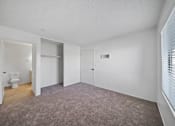 Thumbnail 8 of 11 - A large, empty room with a carpeted floor and white walls.