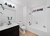 Thumbnail 12 of 13 - A white bathroom with a toilet, sink, and shower.