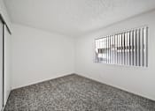 Thumbnail 6 of 13 - A room with a carpeted floor and a window with horizontal blinds.