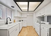 Thumbnail 9 of 13 - A white kitchen with a black ceiling and wooden floors.