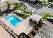 Thumbnail 5 of 8 - An aerial view of a swimming pool surrounded by a fence and a parking lot.