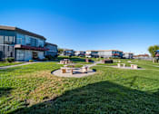 Thumbnail 2 of 20 - A sunny day at a park with picnic tables and a grassy area.