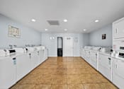 Thumbnail 12 of 12 - A laundromat with a row of washers and dryers.