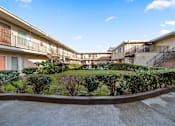 Thumbnail 3 of 19 - A sunny day at a residential complex with a clear blue sky.