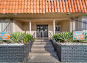 Thumbnail 1 of 19 - A building with a red tile roof has a sign that says "Welcome Home" and "Now Leasing.".