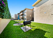 Thumbnail 2 of 8 - A black grill is on a stand in a grassy yard.