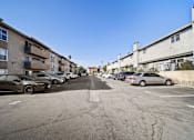 Thumbnail 4 of 8 - A parking lot with cars and apartment buildings on either side.
