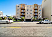 Thumbnail 10 of 10 - A white car is parked in front of a tan building.
