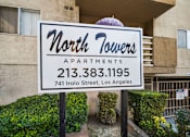 Thumbnail 7 of 10 - A sign for North Towers Apartments stands in front of a building.