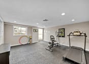 Thumbnail 2 of 10 - A spacious room with a treadmill, exercise bike, and a chair.