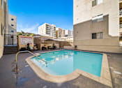 Thumbnail 6 of 10 - A small pool with a diving board is surrounded by buildings.