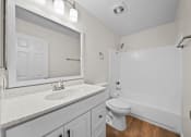 Thumbnail 12 of 16 - A white bathroom with a toilet, sink, and bathtub.