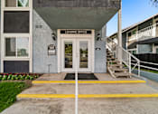 Thumbnail 2 of 16 - A building with a leasing office entrance has a yellow line painted on the concrete.
