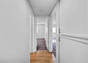 Thumbnail 9 of 16 - A hallway with white walls and a grey carpet.