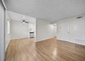 Thumbnail 4 of 16 - A spacious room with wooden flooring and white walls.