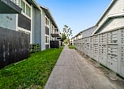 Thumbnail 3 of 16 - A long concrete walkway leads between two rows of mailboxes.