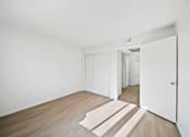 Thumbnail 12 of 13 - A room with white walls and a wooden floor with a rug in the middle.
