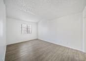Thumbnail 8 of 13 - A room with a window and wooden flooring.