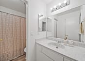 Thumbnail 7 of 11 - A bathroom with a sink, mirror, and shower curtain.