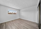 Thumbnail 8 of 16 - Empty room with wooden flooring and a window.