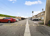 Thumbnail 11 of 16 - A red car is parked on the left side of a street.