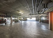 Thumbnail 4 of 15 - A parking garage with cars parked and a concrete floor.
