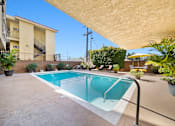 Thumbnail 5 of 15 - A small pool in a backyard with a building in the background.