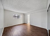 Thumbnail 12 of 18 - A room with a wooden floor and white walls.