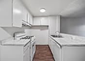 Thumbnail 14 of 18 - A kitchen with white cabinets and a marble countertop.