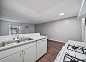 Thumbnail 16 of 18 - A kitchen with a stove, sink, and cabinets.
