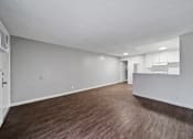 Thumbnail 11 of 18 - A large empty room with wood flooring and white walls.