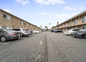 Thumbnail 6 of 18 - A parking lot with cars parked in front of apartment buildings.