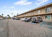 Thumbnail 7 of 18 - A parking lot with cars and apartment buildings in the background.