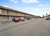 Thumbnail 8 of 18 - A parking lot with cars and apartment buildings in the background.