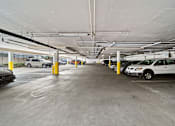 Thumbnail 4 of 7 - A parking garage with cars parked and yellow bollards.