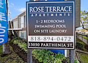 Thumbnail 3 of 11 - A sign for Rose Terrace Apartments with a swimming pool on site.