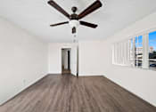Thumbnail 9 of 21 - A room with a ceiling fan and wooden flooring.