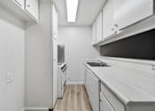 Thumbnail 8 of 10 - A kitchen with white cabinets and a black counter top.