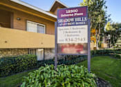 Thumbnail 2 of 10 - A sign for Shadow Hills Apartment Homes is in front of a building.