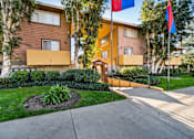 Thumbnail 3 of 10 - A building with a brown and yellow exterior and a small garden in front.