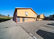 Thumbnail 7 of 10 - A yellow building with a grey parking lot in front.