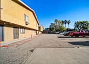 Thumbnail 8 of 10 - A parking lot with a red car and a yellow building.
