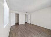 Thumbnail 13 of 16 - A room with white walls and wooden flooring with three doors.