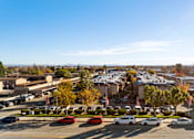 Thumbnail 6 of 16 - A parking lot with cars and a building in the background.