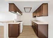 Thumbnail 14 of 16 - A kitchen with brown cabinets and a white counter.