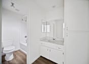 Thumbnail 11 of 11 - A white bathroom with a toilet, sink, and mirror.
