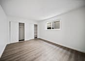 Thumbnail 9 of 11 - Empty room with a window and wooden flooring.