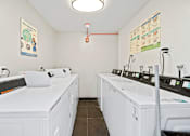 Thumbnail 7 of 11 - A laundromat with white washers and dryers.