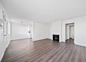 Thumbnail 6 of 11 - A large, empty room with a fireplace and wood flooring.