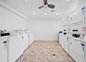 Thumbnail 5 of 6 - A room with a white ceiling and floor, containing a row of washing machines.